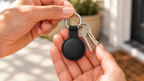 Close-up van de zwarte sleutelhanger met twee huissleutels in de hand, in warm daglicht
